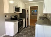 Thumbnail 35 of 47 - A kitchen with white cabinets and a black refrigerator.