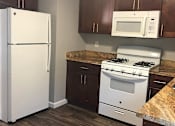Thumbnail 14 of 22 - A kitchen with a white fridge, white microwave, and white stove.