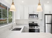 Thumbnail 22 of 33 - A modern kitchen with a black stove top oven and a black refrigerator.