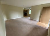 Thumbnail 33 of 51 - an empty living room with a carpeted floor and an open door to a kitchen
