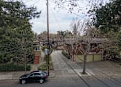 Thumbnail 10 of 38 - A black car is parked on a street with a telephone pole in the foreground.