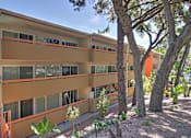 Thumbnail 11 of 23 - A building with orange and beige colors surrounded by trees.