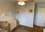 Thumbnail 27 of 32 - a nursery with a crib and a ceiling fan