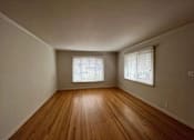 Thumbnail 23 of 38 - A room with wooden floors and two windows with blinds.