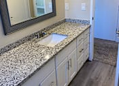 Thumbnail 6 of 43 - A bathroom with a granite counter top and white cabinets.
