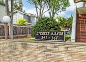 Thumbnail 3 of 33 - A sign for the Evergift Manor apartment complex is displayed in front of a brick wall.