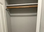 Thumbnail 25 of 33 - A small, empty closet with a white door and a shelf above the carpeted floor.