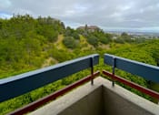 Thumbnail 6 of 6 - a balcony with a view of trees and a building in the distance