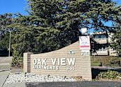 Thumbnail 1 of 6 - A sign for Oak View Apartments is in front of a tree.