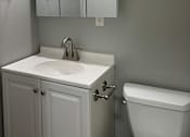 Thumbnail 16 of 18 - A white bathroom with a toilet, sink, and light fixture.