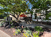 Thumbnail 16 of 19 - A leasing office is surrounded by trees and plants.