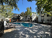 Thumbnail 2 of 19 - A pool surrounded by trees and chairs.