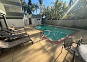 Thumbnail 7 of 23 - A pool surrounded by chairs and trees.