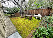 Thumbnail 11 of 38 - A backyard with a wooden fence and a green lawn.