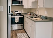 Thumbnail 4 of 16 - a small kitchen with white cabinets and black appliances