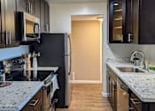 Thumbnail 4 of 11 - a kitchen with black cabinets and granite counter tops and a stainless steel refrigerator