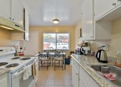 Thumbnail 22 of 36 - A kitchen with a white stove top oven and white cabinets.