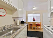 Thumbnail 29 of 36 - A kitchen with a table and chairs in the middle of it.