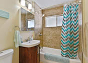 Thumbnail 19 of 36 - A bathroom with a white bathtub, a sink, a mirror, and a shower curtain.
