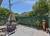 Thumbnail 20 of 36 - A patio with a table and chairs and a green fence.