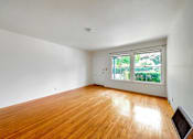 Thumbnail 14 of 25 - an empty living room with wood floors and a window
