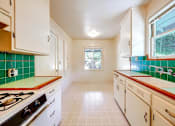 Thumbnail 9 of 25 - a kitchen with green tile and white cabinets