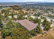 Thumbnail 1 of 10 - A large building with a brown roof is surrounded by trees and is located in a residential area.