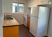 Thumbnail 7 of 13 - A kitchen with a white refrigerator and orange counter.