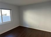 Thumbnail 6 of 13 - A room with a window and wooden flooring.