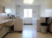 Thumbnail 4 of 6 - A clean, empty laundry room with washers and dryers.