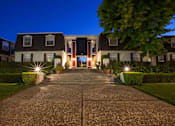 Thumbnail 4 of 51 - a large house with a driveway in front of it at night