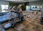 Thumbnail 2 of 6 - A gym with treadmills, elliptical machines, and weights.