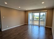 Thumbnail 7 of 11 - an empty living room with wood floors and a sliding glass door