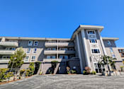 Thumbnail 3 of 11 - an apartment building with a parking lot and a blue sky