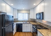 Thumbnail 13 of 30 - a kitchen with white cabinets and granite counter tops and a black refrigerator