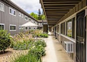Thumbnail 10 of 30 - a walkway between a row of buildings with plants and flowers
