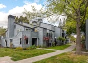 Thumbnail 1 of 20 - exterior view of a gray house with sidewalk and trees