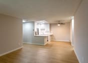Thumbnail 13 of 20 - an empty living room and kitchen with wood flooring and a ceiling fan