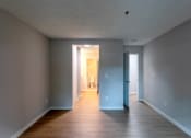 Thumbnail 16 of 20 - an empty living room and hallway with wood floors and grey walls