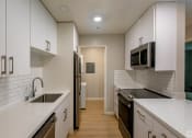 Thumbnail 12 of 20 - an empty kitchen with white counters and a sink and a refrigerator