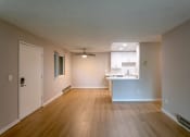 Thumbnail 11 of 20 - an empty living room and kitchen with wood floors and a ceiling fan