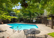 Thumbnail 3 of 16 - a swimming pool in a backyard with a table and chairs