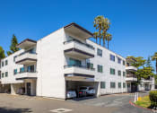Thumbnail 16 of 16 - a white apartment building with cars parked in front of it