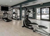 Thumbnail 3 of 15 - A gym with treadmills, elliptical machines, and a television.
