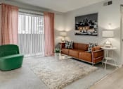 Thumbnail 5 of 15 - A living room with a green chair, a brown sofa, and a white side table.