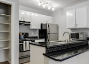 Thumbnail 7 of 15 - A kitchen with black granite countertops and white cabinets.