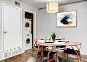 Thumbnail 11 of 15 - A dining room with a table set for two and a washing machine in the background.