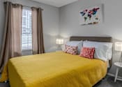 Thumbnail 14 of 15 - A bedroom with a yellow bedspread and a world map artwork on the wall.
