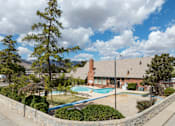 Thumbnail 4 of 8 - A swimming pool surrounded by a stone wall and trees.