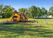Thumbnail 10 of 15 - A playground with a yellow slide and a green swing set.